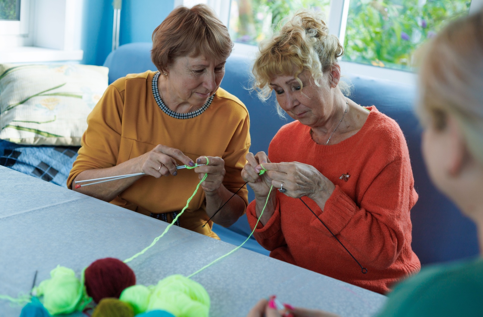 A couple of senior ladies enjoying knitting together in their community common area.