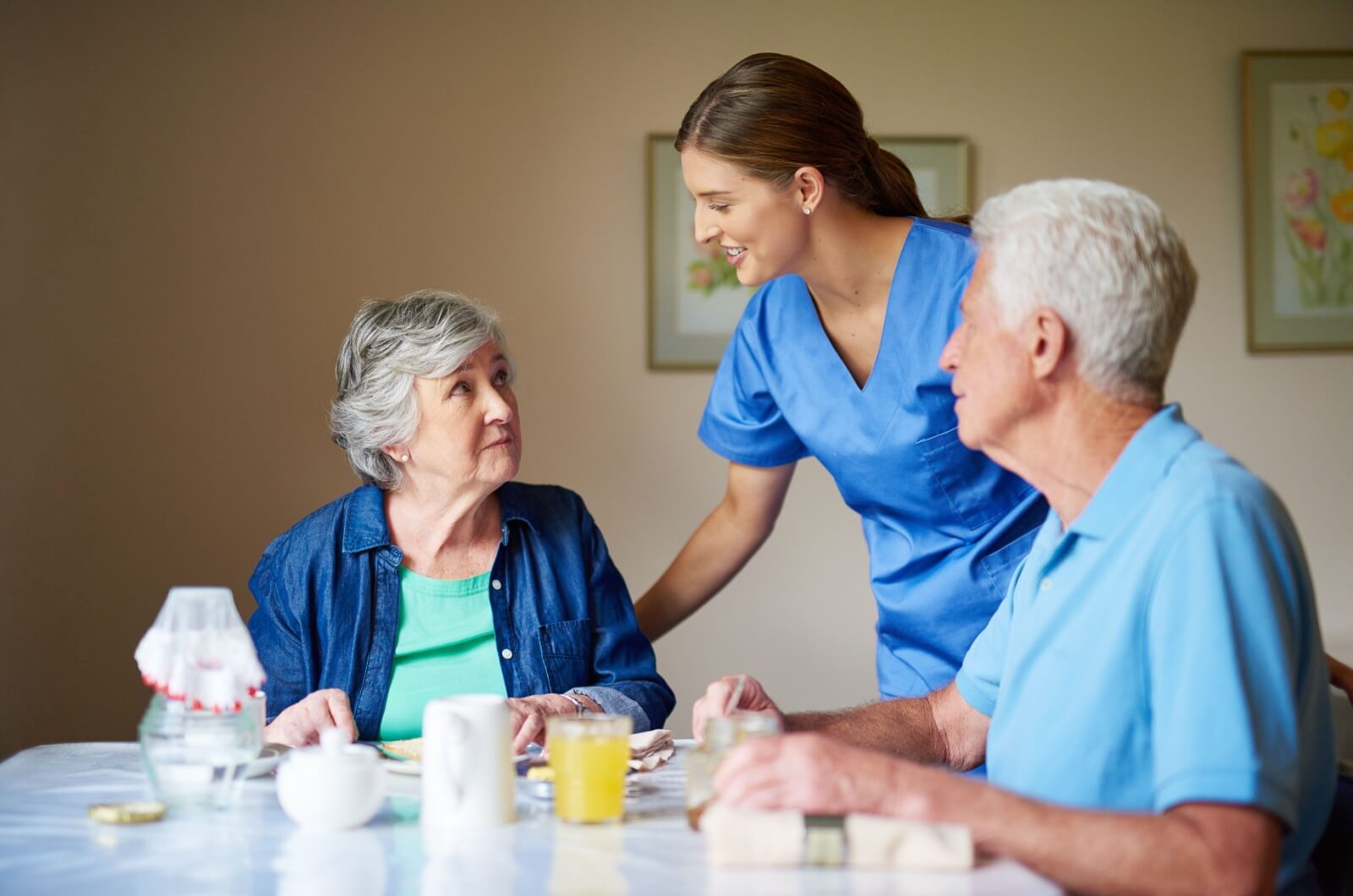 A staff member checks in with an older couple in assisted living.