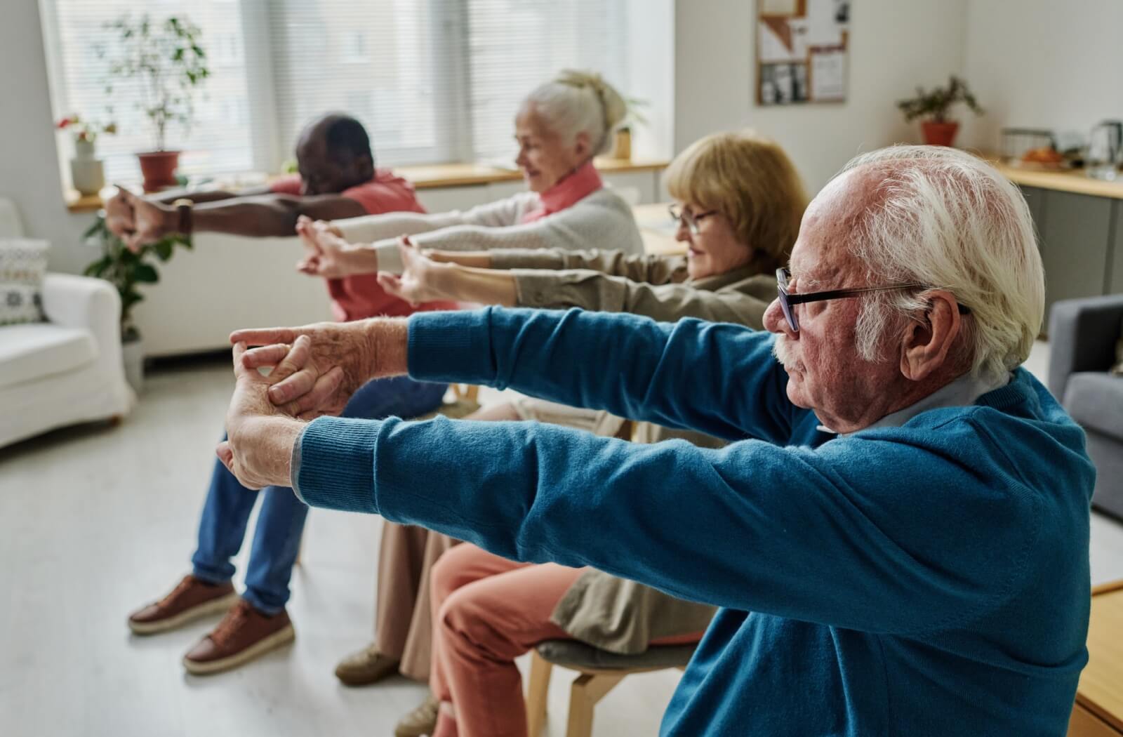 A group of older adults in an indoor pool using foam weights during a water aerobics class.