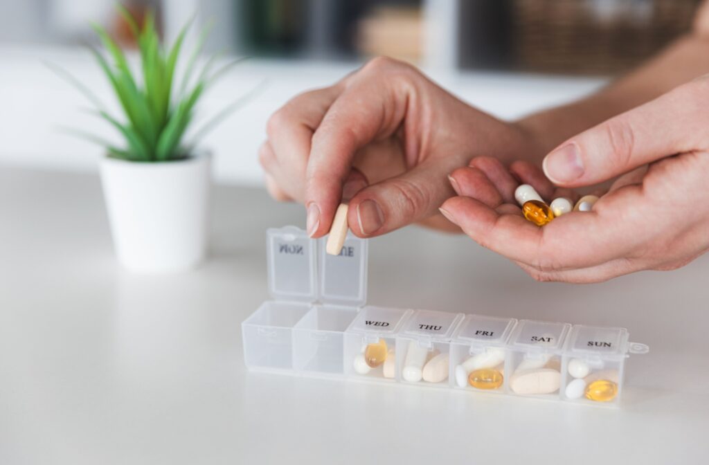 A close-up image of a caregiver preparing a senior's weekly medications and supplements.