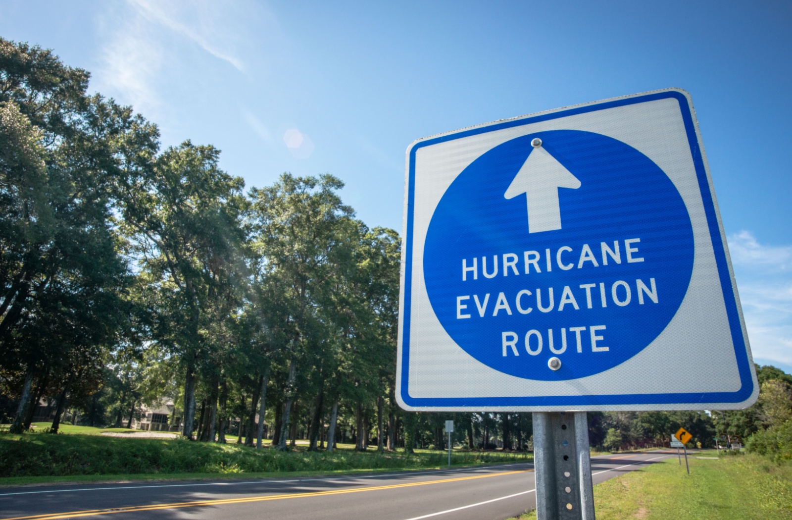 A sunlit sign on the side of the road with the words "Hurricane Evacuation Route" on it.