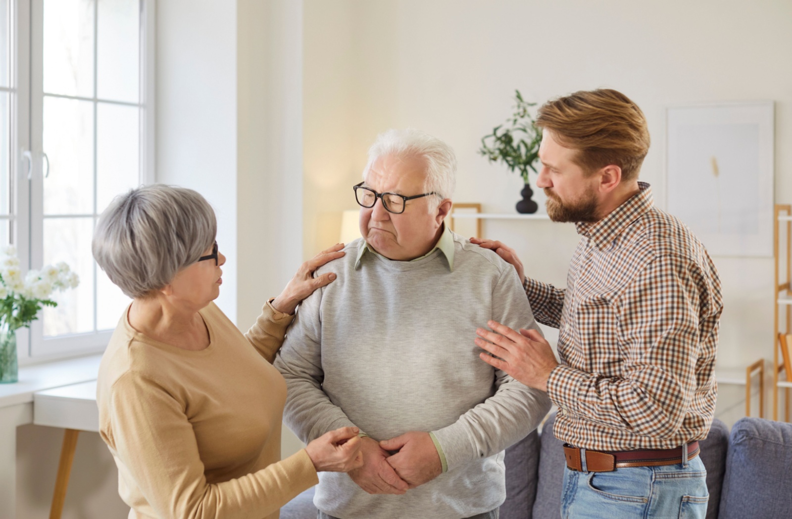 Senior being comforted by adult children in a bright home setting showing empathy and support during a serious conversation