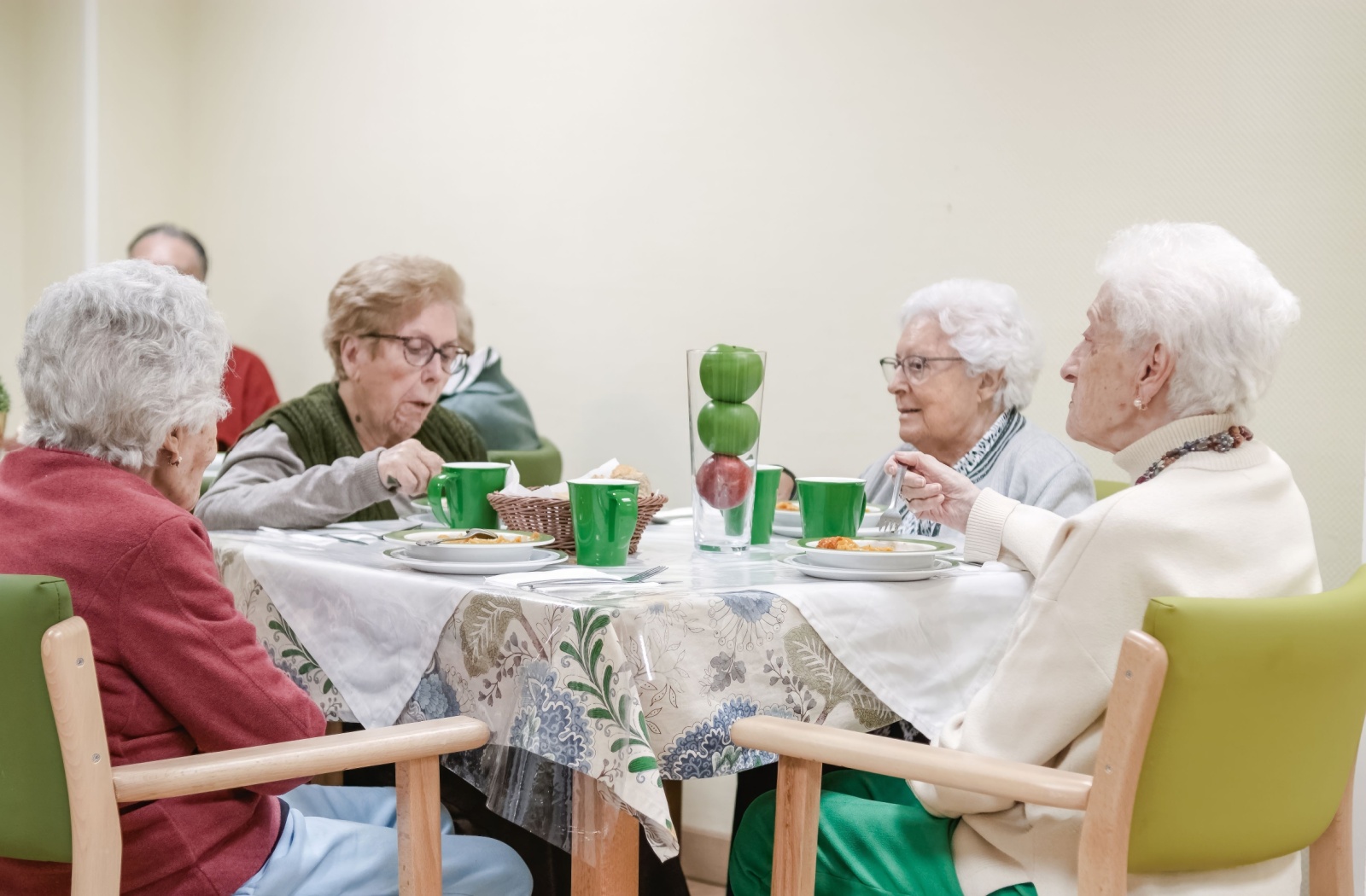 A group of seniors share a meal at a table in an assisted living community
