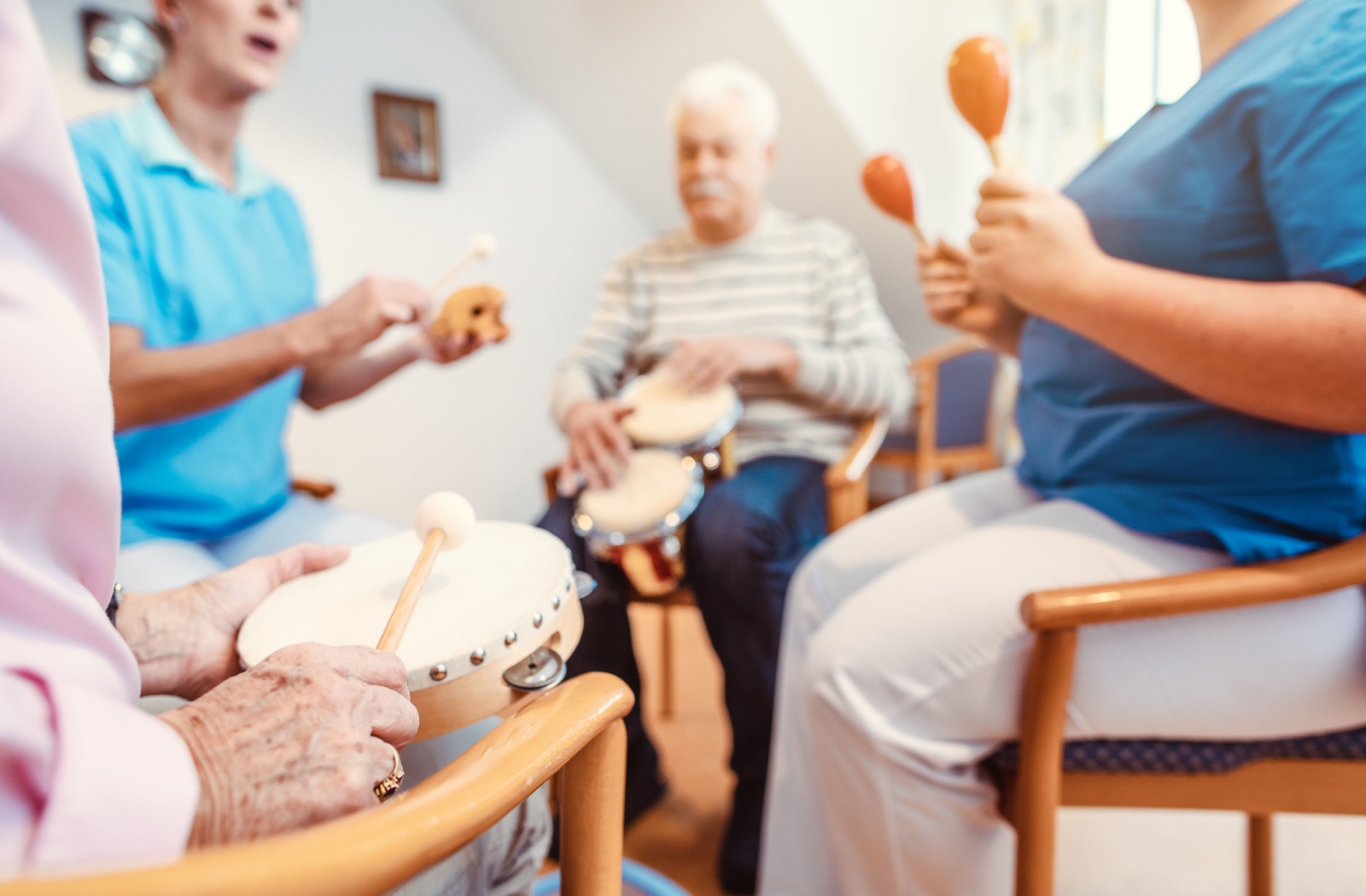 A group of older adults participate in a live music therapy workshop at a senior living community.