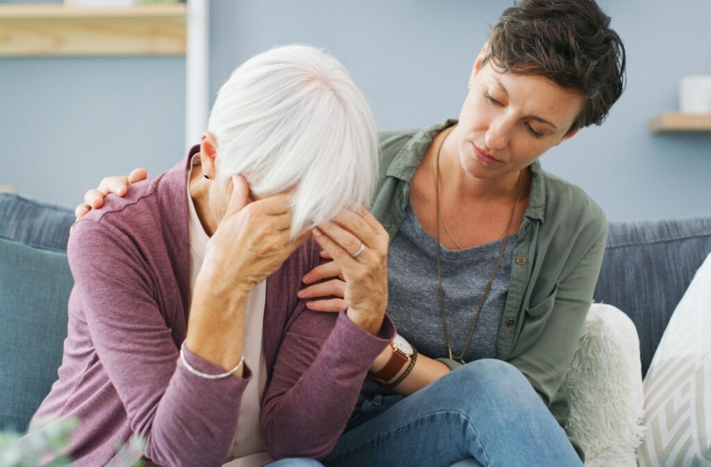 An adult family member comforts their upset loved one with dementia.
